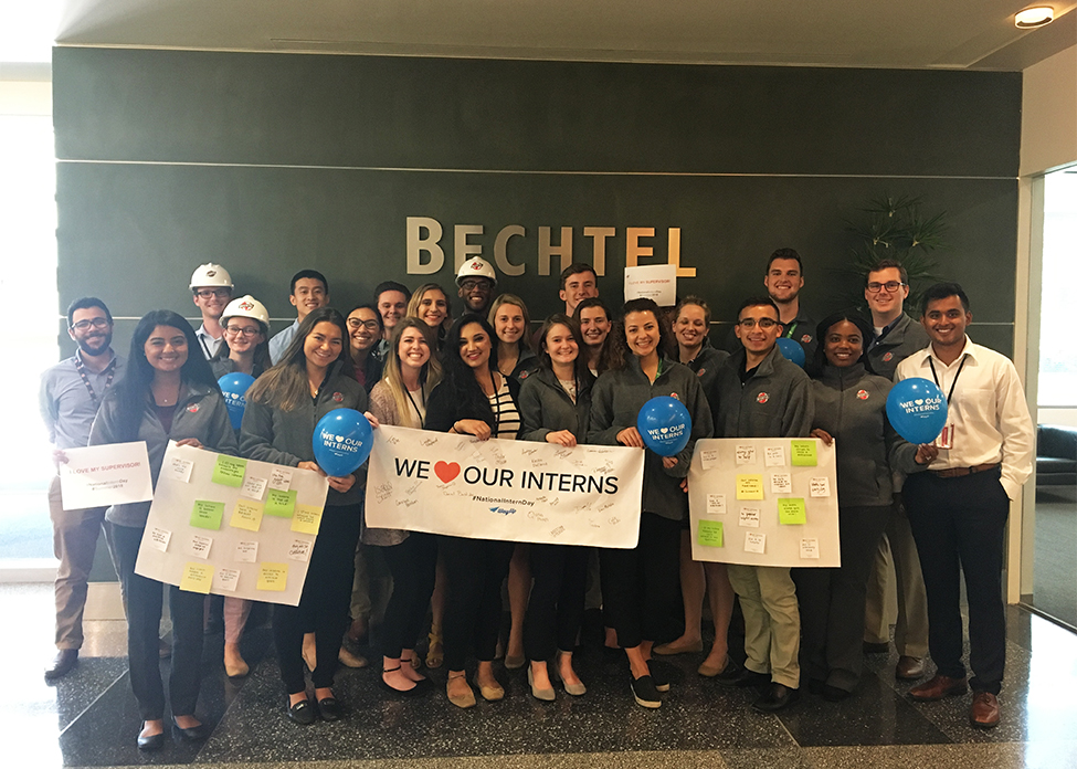 A group of Bechtel interns pose in the lobby holding a sign that reads 'we love our interns'