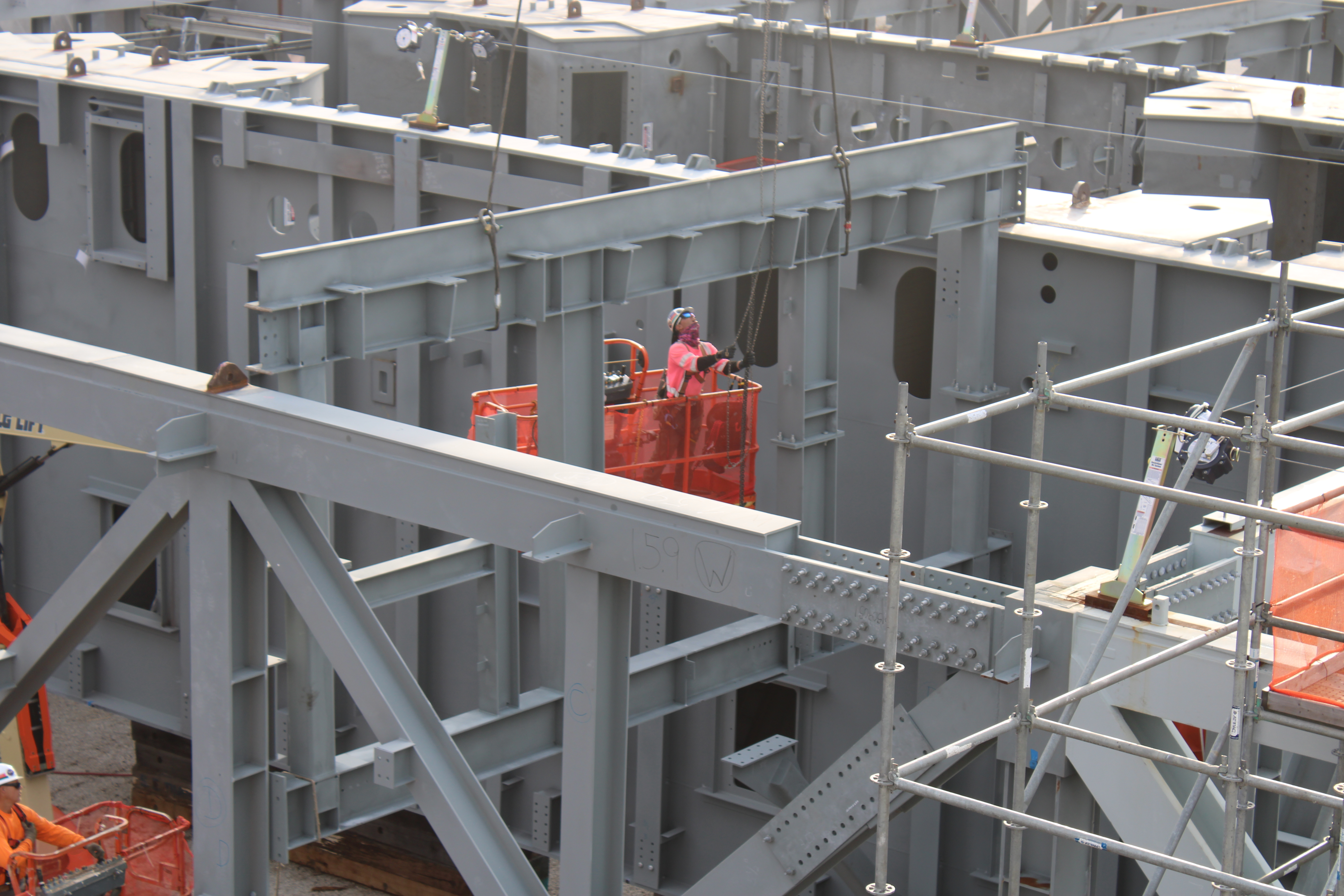 An ironworker guides a truss into place on the mobile launcher 2 base.