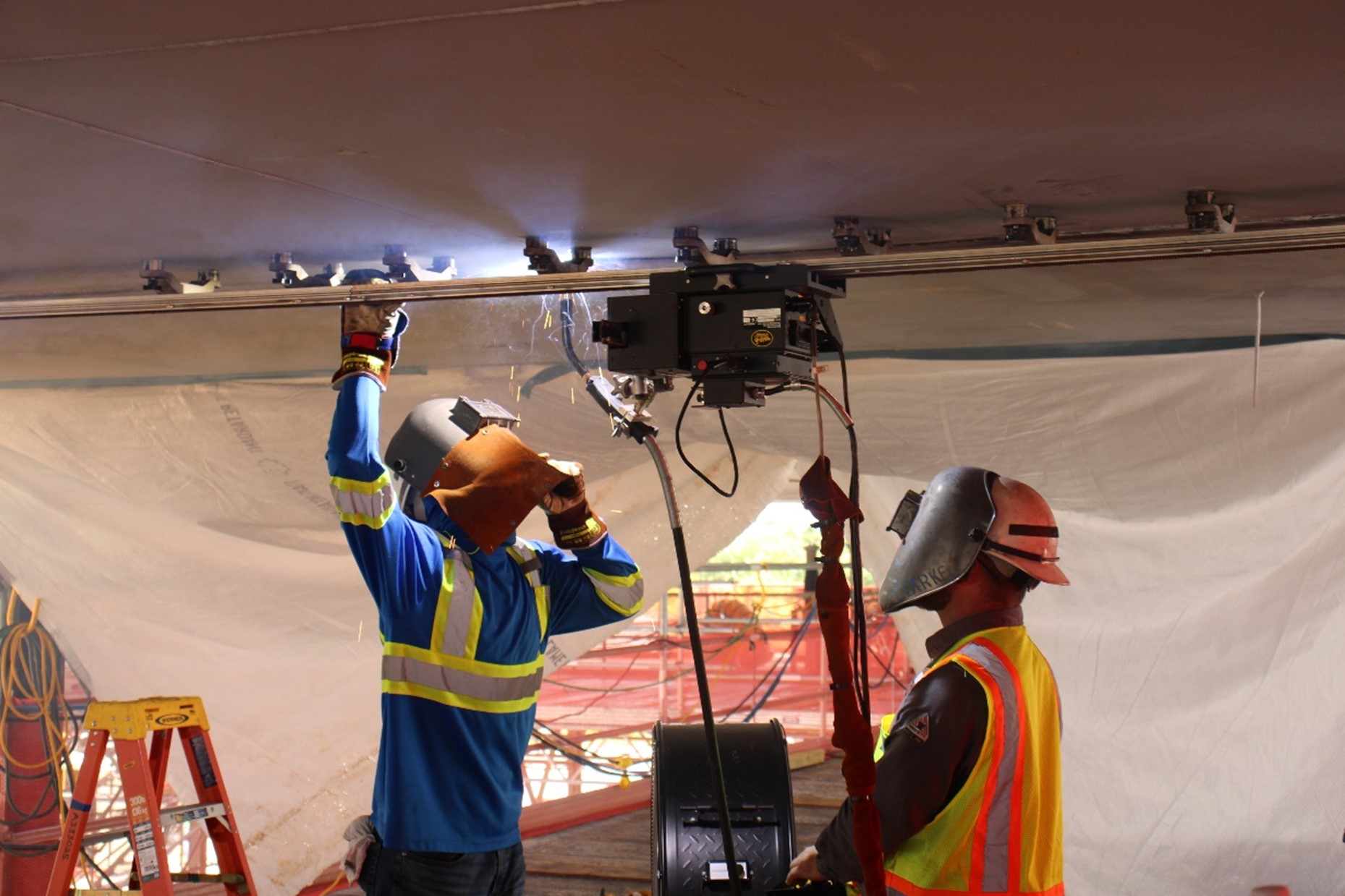 Ironworkers use semi-automatic welding equipment to efficiently weld base panels.