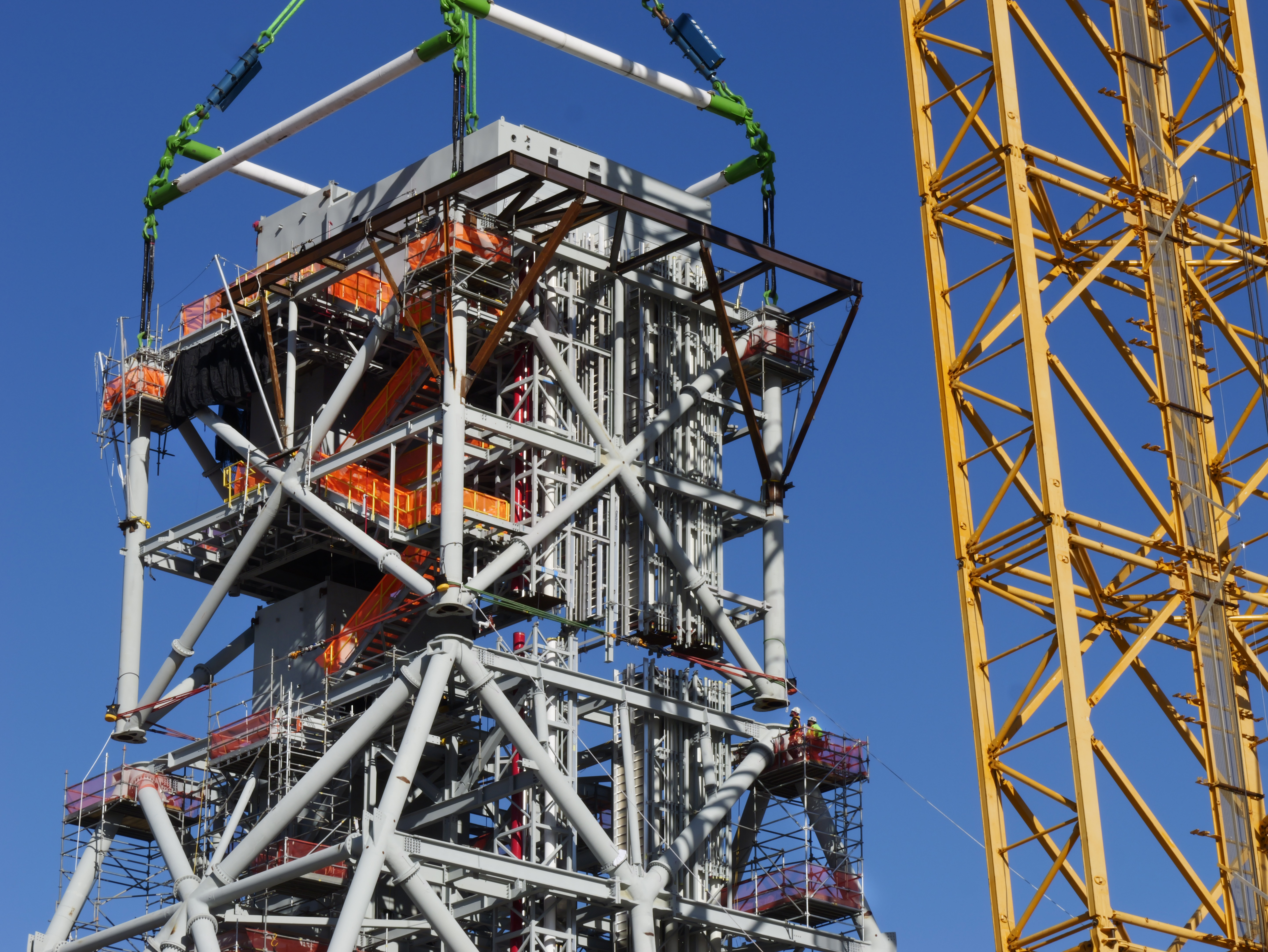 Mod 4 is lowered onto the tower chair while Ironworkers are at the ready to set connections after touchdown. 