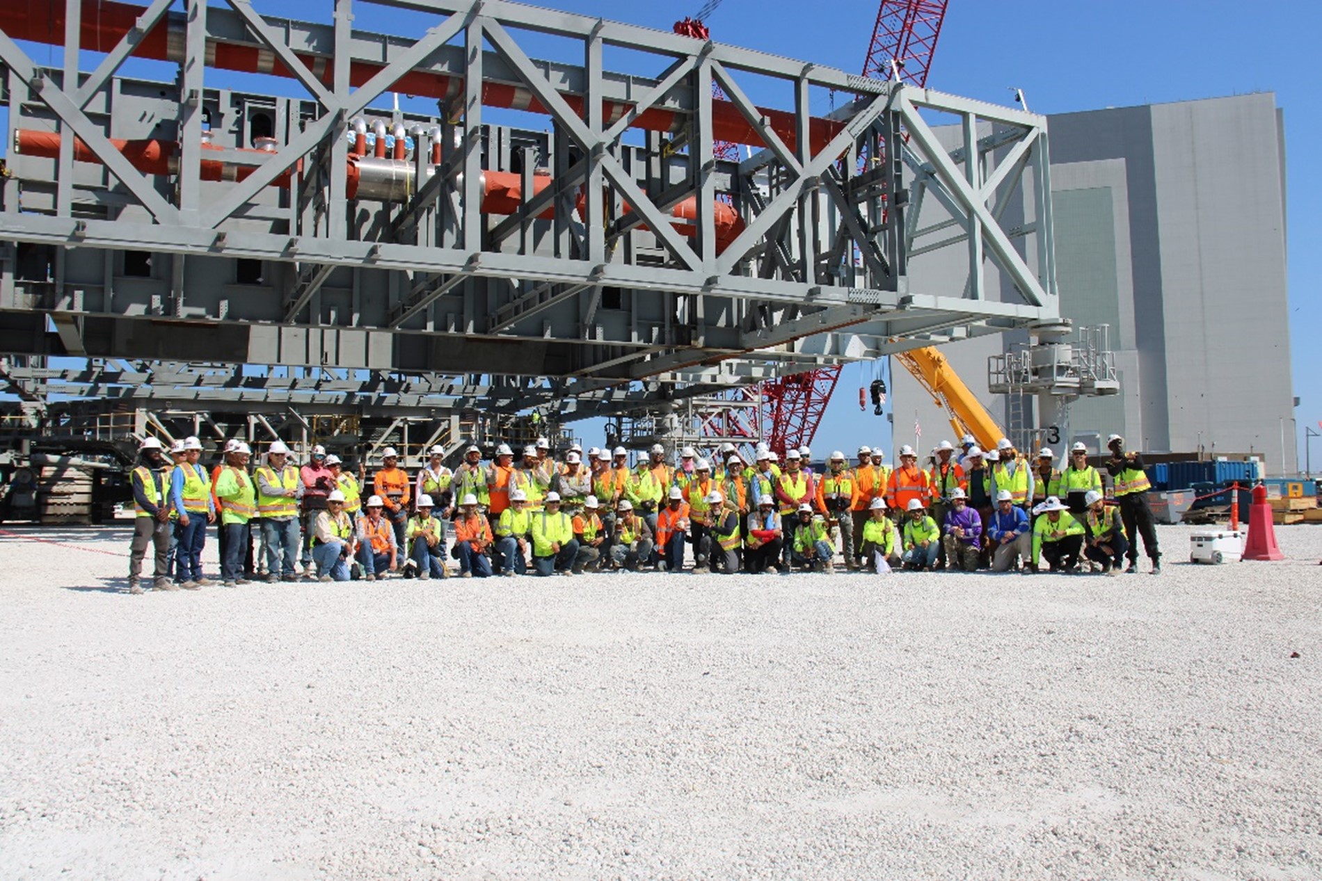 Craft professionals from the Bechtel Mobile Launcher 2 team pose with the base, VAB, and crawler after the successful completion of the Jack and Set operation.