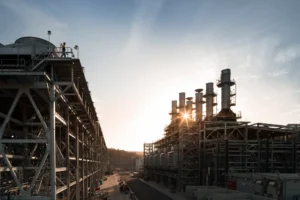 The Australia Pacific LNG train 1 compressor deck with blue sky and a sun flare in the background.