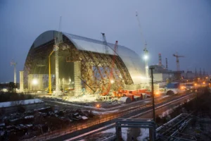 Exterior view of the New Safe Confinement (NSC) under construction at night.